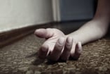 A hand lies on the floor after a drug addict overdoses on grey death.