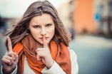 girl with silencing finger gesture