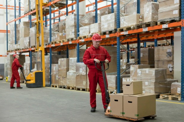 wholesale worker in warehouse operating machinery carrying boxes of merchandise