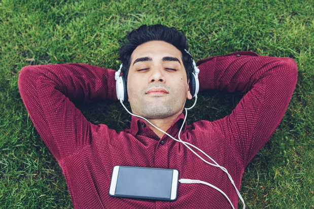 A recovering addict lies on the grass, as he listens music.