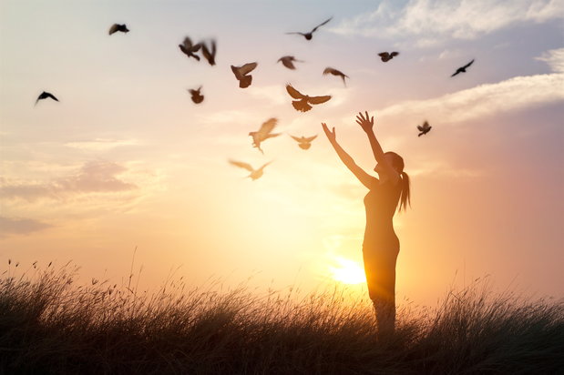 woman prays as birds fly