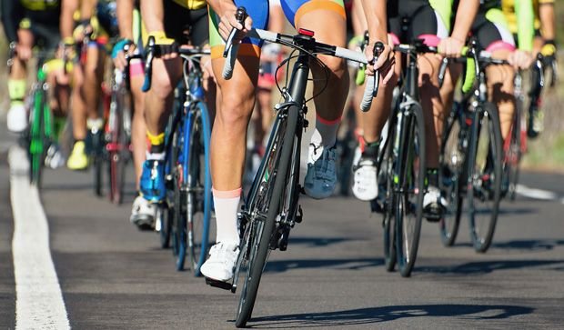 Group of cyclists race on a road showing their legs.