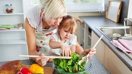 A mom making a salad with her daughter.