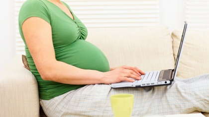 A pregnant woman on her laptop.