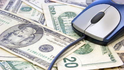 A computer mouse surrounded by cash. 