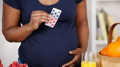 Pregnant woman holding pills.
