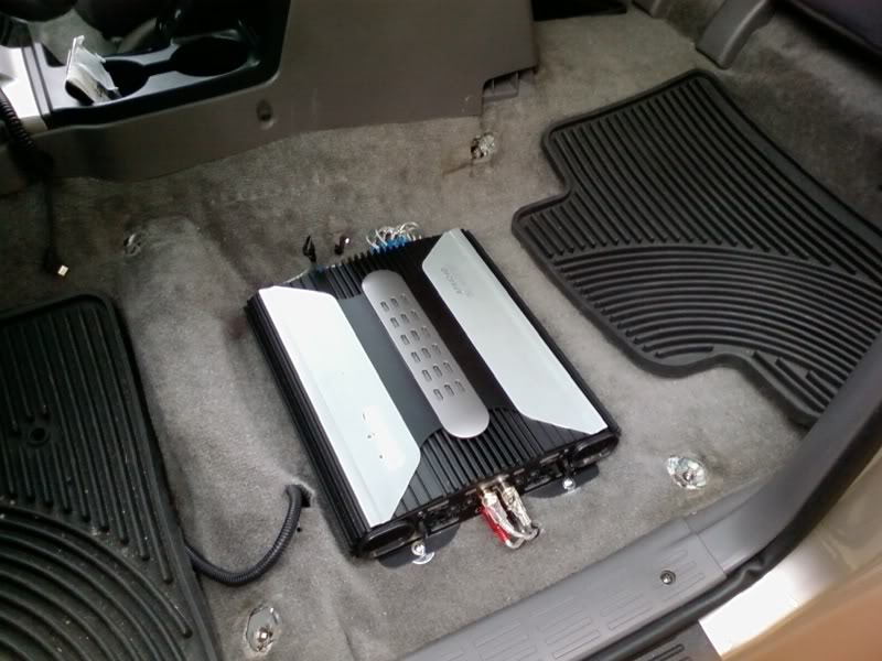 Aftermarket Clarion amplifier mounted to floorboard under the driver's seat