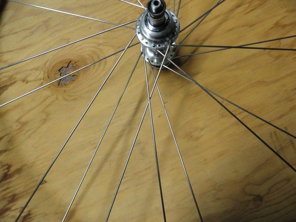 The spokes are placed into the hub from the inside to the outside.  And then laced over two and under one spoke for it's final position.  The way it looks in place