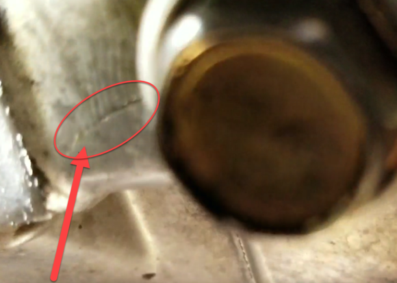 Crack line on belly of oil pan. This crack goes all the way done to where the bolt head meets the pan.