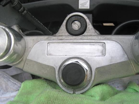 Cleaning the top triple clamp to prepare for restoration of original appearance.