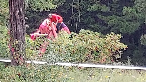 My wife in the pink top and pink tutu on the backside of the top of a large climbing wall obstacle