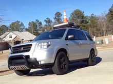 Moved LED bar to up top (mounted on roof basket) Spare BF Goodrich M/T and cone just for fun. Also finally cleared my headlights of the Orange pieces!