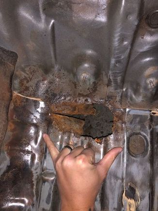This is the largest of all holes, right in the top left corner where the floorboard bends up to the firewall and center hump.