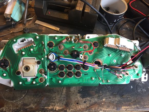 This is the rear of the cluster all wired up. I was able to steal power and tach signal from the stock cluster board so there won't need to be additional wiring. Also as I'm sure you can tell the plug socket that was originally flush mounted had to be cut out and mounted outside to accommodate the Ultra tach. Also you can see where I was able to mount the new bulb that lights the two center gauges.