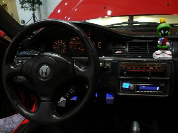 The wheel is a JDM EP3/DC5 Momo wheel with an AP1 S2000 airbag. I had to use a 96-00 Civic steering column to make it work. Also used an S2000 clock spring to hook up the cruise, horn, and airbag. I did all the custom splicing under the dash.

The cluster is a mixture of my original USDM cluster and a JDM Vti cluster. I am running the red lit needles and #74 amber bulbs. It is dead on accurate in looks and function and I don't have to convert kilometers to miles in my head by a factor of 0.62. My mileage is 100% legal.