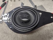 I traced the shape of the OEM mounting plate onto a piece of Lexan than then cut it out with my band saw and hole saw in a drill press.  I had to break off one of the 4 speaker mounting tabs to prevent interference with the speaker grill mounting slots.  I used a bracket I have for mounting things into slatwall which fit into the slot in the car to hold it perfectly.  Once I had the plate built, I covered it with some black vinyl so it would look good through the speaker grill.
