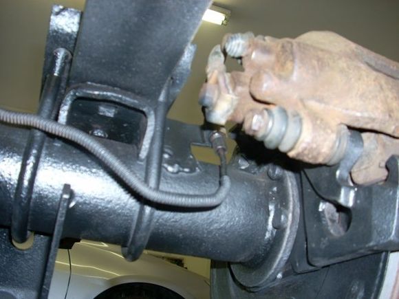 Rear Disc brake upgrade: Picture of soft brake line bracket (right of axel U-bolt) from a Grand Cherokee, welded on my Chrysler 8.25" axel. Hard line is off the Cherokee axel but bent to fit Grand Cherokee soft line at bracket mount. I have a technical article on a better way to hook parking brake cable up. Works better than looping it!