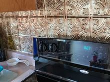 Our back splash was just drywall , so I bought these plastic replica “tin” ceiling tiles and used RTV clear silicone to adhere them to the wall, they are 2’x4’ sheets so lotsa room to match up the pattern. They’ve been up there for about 15 years now! 