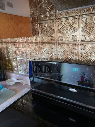 Our back splash was just drywall , so I bought these plastic replica “tin” ceiling tiles and used RTV clear silicone to adhere them to the wall, they are 2’x4’ sheets so lotsa room to match up the pattern. They’ve been up there for about 15 years now! 