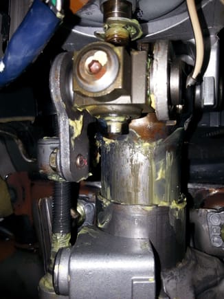 An image taken of bottom view up of the steering column with upper and lower covers removed. The threaded allen head cap is shown near top of this image in center of tilt pivot block...requires  a 4 mm allen wrench to remove.