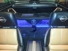 Custom subwoofer box with LEDs, two tone leather seats with emblem, custom rear speaker housings, speakers, matching grill frame, and custom grills.