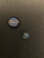 The smaller item is a ball marker, and the reverse side has a small spike to keep it in place in the grass. 

