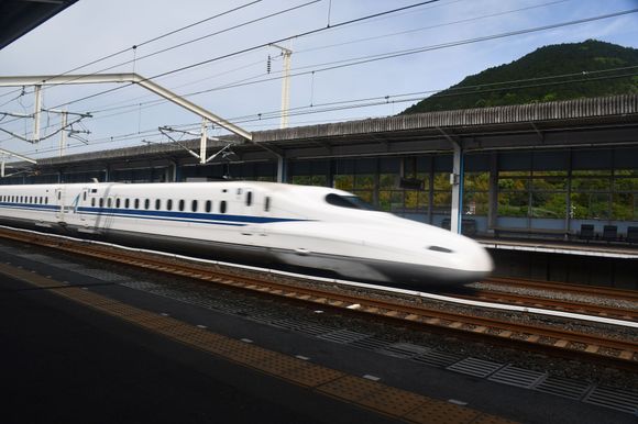 Shinkansen ( Nozomi probably) going on the two centre tracks  heading to Hakata probably. Taken at Shin -Iwakani. Slower trains ( Kodama) use  the  tracks by the platforms then join the fast tracks. No platform barriers here .