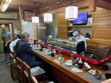 There are about 8 seats around the bar and two small tables. You can see some sushi on the lip of the bar.
