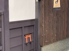 The miniature torii, normally seen at Shinto shrines, is considered an entrance to a spiritual place. Here it is placed low on a building wall within an area with a lot of bars to prevent drunken guys from urinating on the building!
