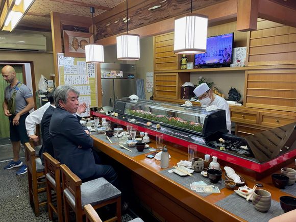 There are about 8 seats around the bar and two small tables. You can see some sushi on the lip of the bar.
