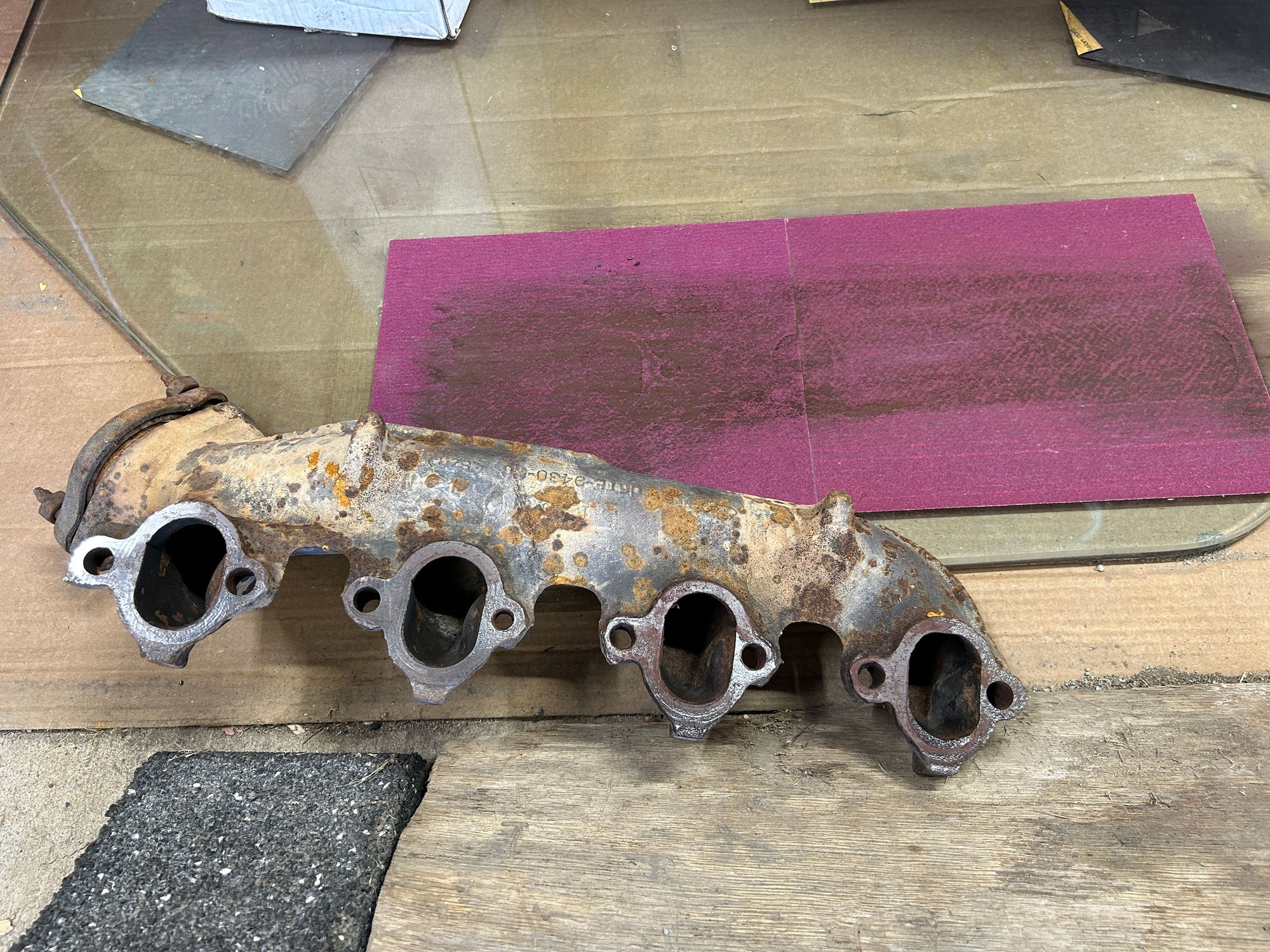 I keep this old glass table top that I use to flatten stuff. My dad brought it home years ago and was always going to build a base for it, but he never got around to it so I talked him out of it years ago and I always use it when I�m restoring old hand planes for woodworking. And I thought this would be a good use to try and flatten the manifolds the best I could. So I just glued some sandpaper to it and then by hand just grinding away. This took a really long time.