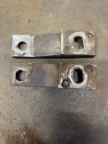 Clutch linkage swivel arm showing ovalized hole on bottom and after weld buildup and filed to fit, above