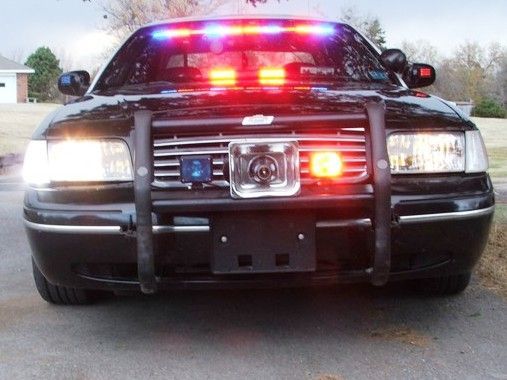 1998 P-71 Ford Crown Victoria, 4.6, this car will do over 
150 mph. It has had a few upgrades that are a tad secret. It has many different types of new and used emergency vehicle equipment. Starting with the ____ Visor LED Red/Blue/ lights. it also has the ____ tri-Red-Blue-Red LED light bar, It has ____ mirror mounted Red/Blue LED lights, it has front Red/Blue strobes imported from China, It has a TWO HUNDRED what siren speaker set up. it has two 100 watt siren speakers screwed into a "Y" and a single Chrome Siren Bell from ________. It has Go-Rhino pushbars. It has a 100 watt aircraft landing light in the spotlight. It has multi-functional headlight flasher and two of six clear strobe lights with a 90 watt power supply. This car has all three levels of light coverage that is needed in a police vehicle. High is the LED Visor lightbar, eye level is the tri-LED lightbar, a lower level are the strobes and the alternating headlights and strobes in the headlights.