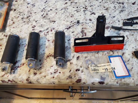 Only 3 of those pegs
Some sort of reflector thst attaches with 4 nuts
Thing in bag: tie down bracket/cable guide from J&P Cycles 
