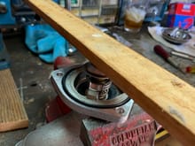 Closeup of the 3ft piece of hardwood that I used to compress the thermostat. Needle nose plyers are good for maneuvering the wings in place.