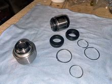 The new spherical bearings, one intact the other with the boots and clips removed. Note almost no grease in the new bearing.