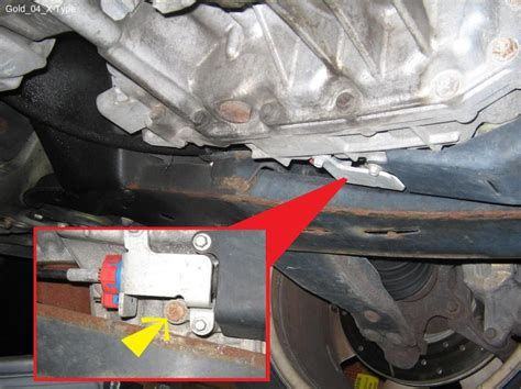 Bottom of transmission, near back of transmission�side of car.  This is the level check plug at the foot of the internal overflow pipe, tube or channel ( not visible).  Drain plug is also visible above and to the left in the larger photo.