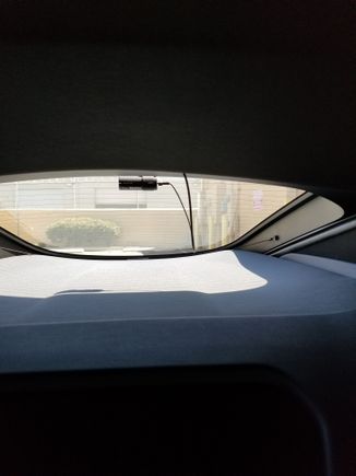 Finally here is the point where the wire comes out from under the trim to meet the camera. That excess wire can be tucked under the headliner trim. I was cleaning the underside of the glass and it came out, but, super easy to hide it all under that headliner.