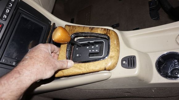 Removal of gear selector bezel: Lifting up at front.