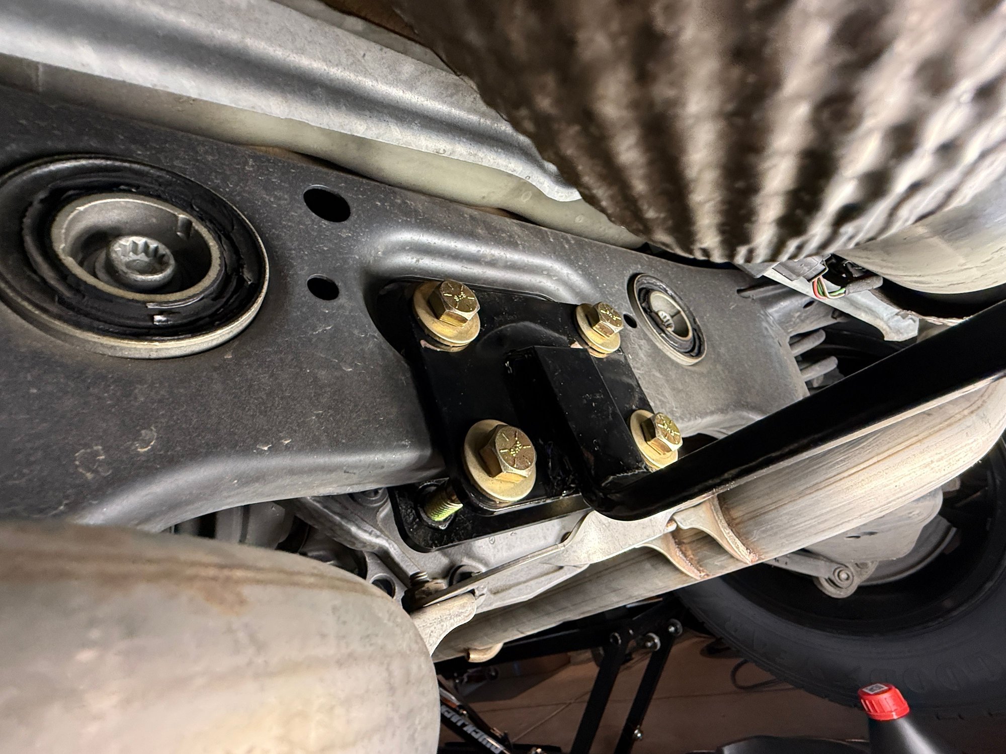 Curt 2 inch reinforcing arm in black as connected to the rear suspension cross frame.