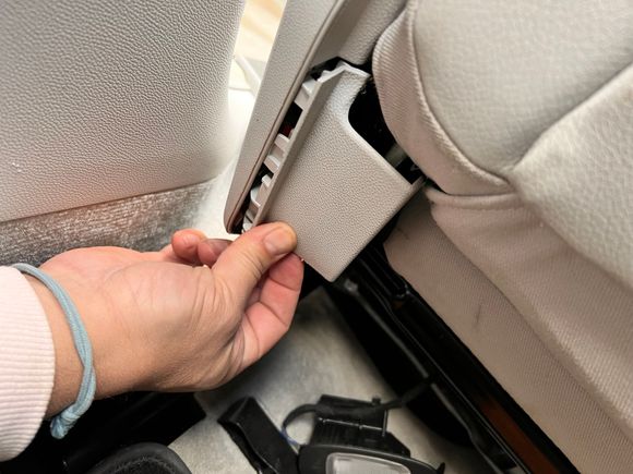 The in er trim piece is long and extends to this part on the backside of the front seat. Just detach it. 