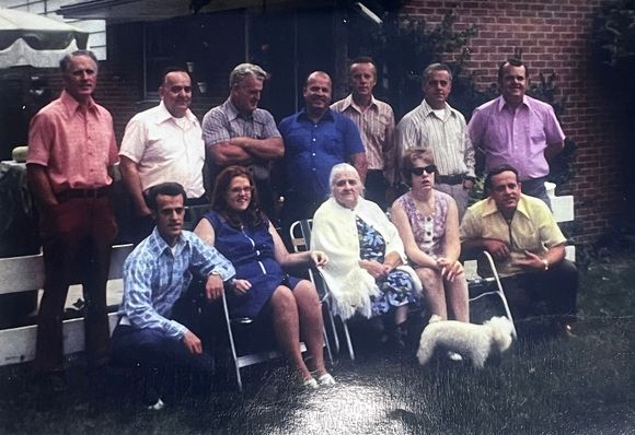 My father is wearing a gray shirt and has his arms folded.