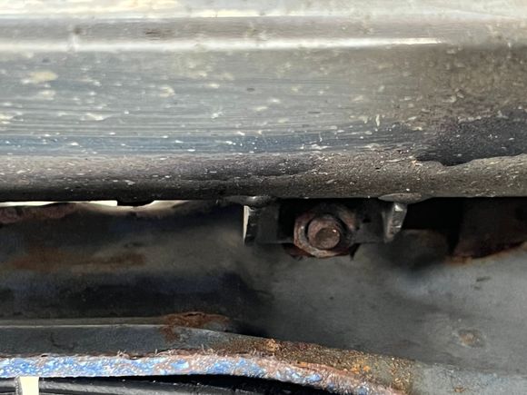 From the engine bay side of the forward bulkhead, looking down at the upper mount of the radiator.J