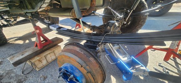 Blocks came in for the rear from Rough Country. 1.5" is the most we could go with out extending the UBolts. Jackstand on the frame, Loosen ubolts, jack under axle. Take one tire off lean axle down, slide block in and loosely snug ubolts. Moved to the other side for same thing. With my rear pipe stand i use on back of truck. I screwed the stamd up to take a little bit of weight off the springs. Took a tape and measuring off the factory spring perches squared the axle relatively close with truck.
